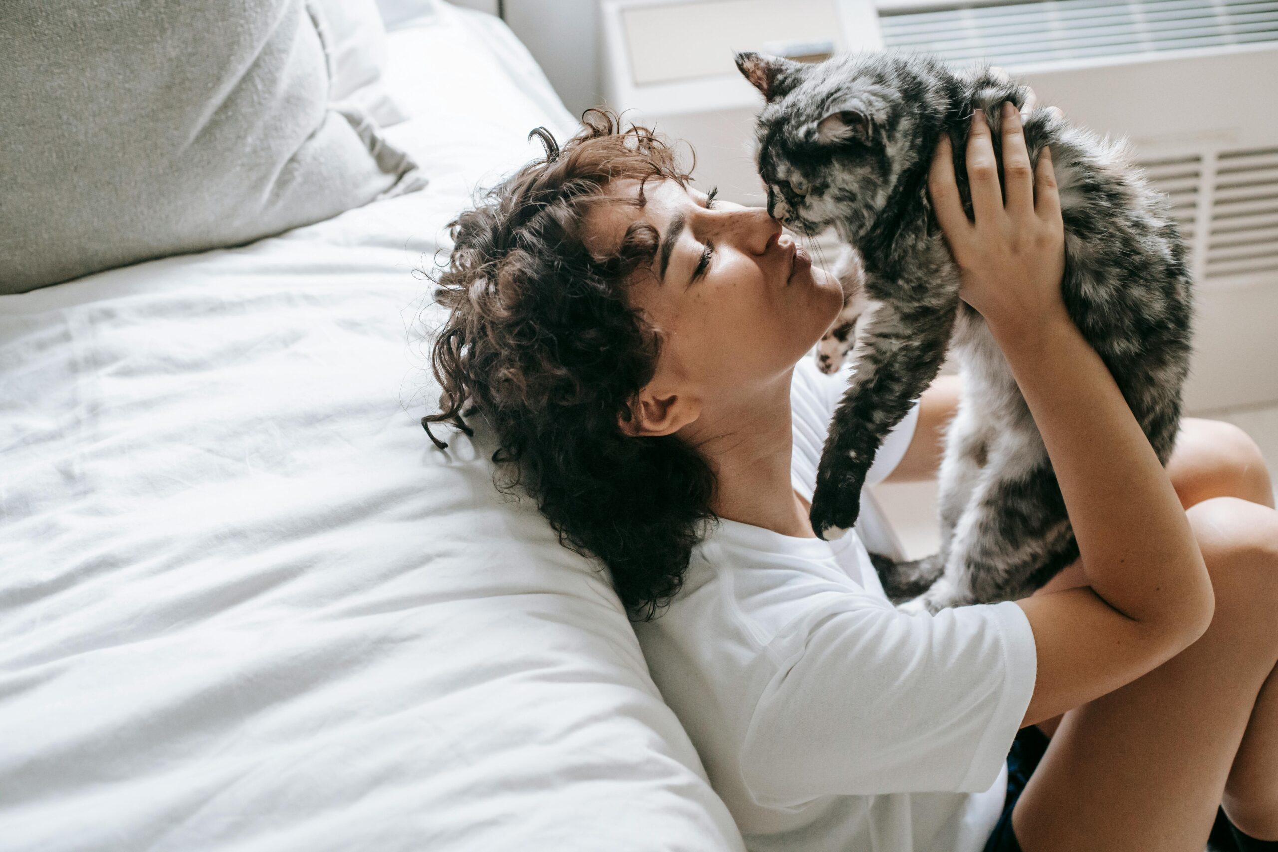Mujer abrazando a gato y dandole un beso en la cabeza